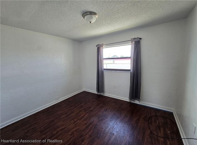 empty room featuring dark hardwood / wood-style flooring and a textured ceiling