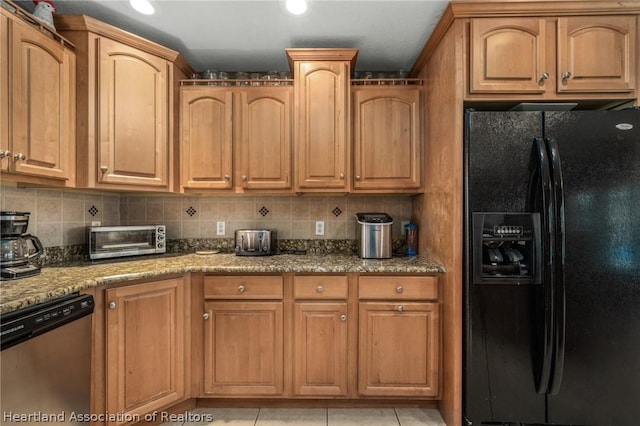 kitchen featuring backsplash, black fridge, light stone counters, light tile patterned floors, and dishwasher