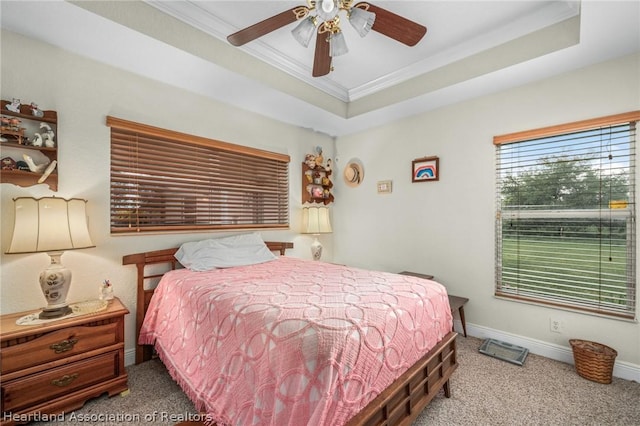 carpeted bedroom featuring a raised ceiling, ceiling fan, and ornamental molding