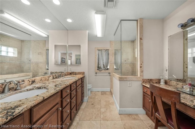 bathroom with tiled shower, vanity, tile patterned flooring, and toilet