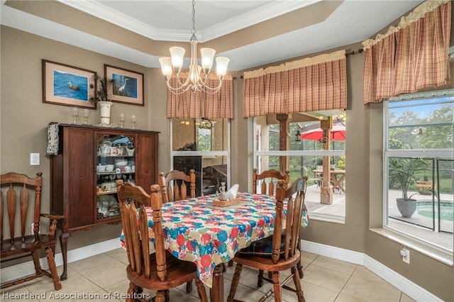 dining area with a tray ceiling, an inviting chandelier, crown molding, and light tile patterned flooring