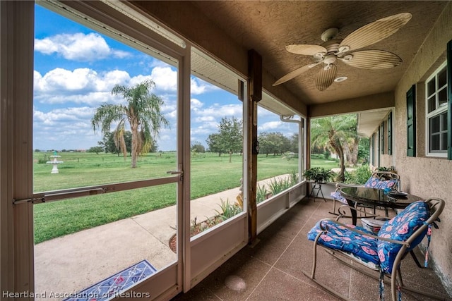 sunroom / solarium with ceiling fan, a rural view, and a wealth of natural light