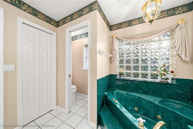 full bath with tile patterned floors, toilet, a closet, and a jetted tub