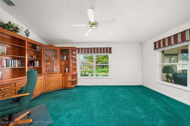 office featuring dark colored carpet, visible vents, ceiling fan, baseboards, and built in study area