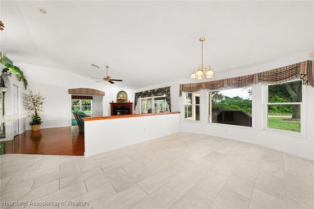 unfurnished living room with ceiling fan with notable chandelier, a fireplace, and vaulted ceiling