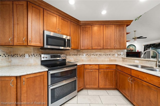 kitchen with a sink, appliances with stainless steel finishes, brown cabinetry, and decorative backsplash