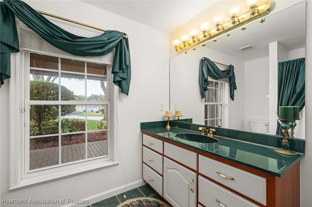 bathroom with visible vents, baseboards, toilet, vanity, and tile patterned flooring