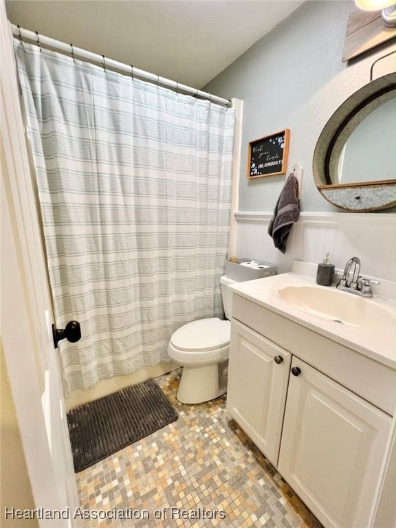 bathroom featuring tile patterned flooring, a shower with curtain, vanity, and toilet