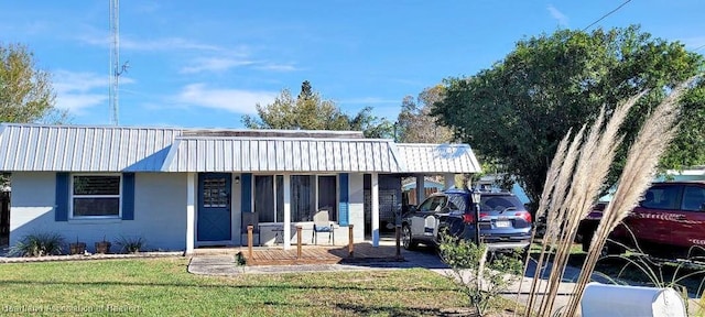 view of front of house featuring metal roof, a front lawn, and covered porch