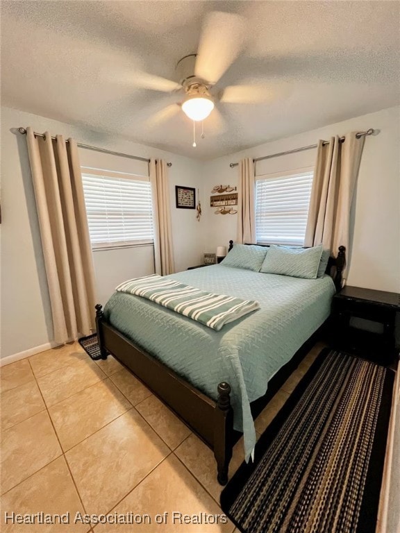 tiled bedroom with ceiling fan and a textured ceiling