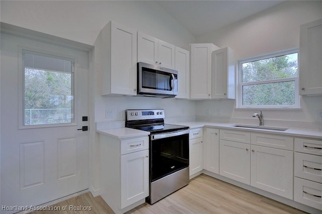 kitchen featuring a sink, appliances with stainless steel finishes, white cabinets, and light countertops