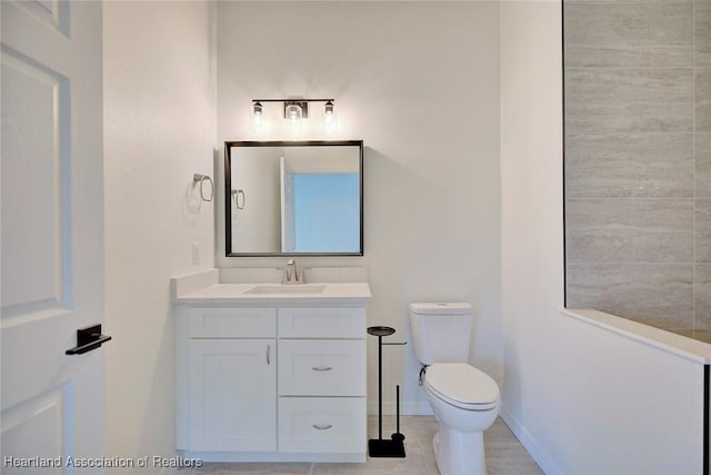 bathroom with toilet, vanity, and baseboards