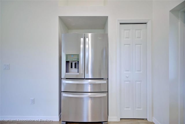 kitchen featuring baseboards, stainless steel refrigerator with ice dispenser, and light wood finished floors