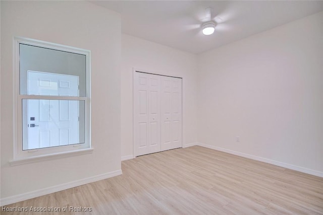 unfurnished room with light wood-type flooring, baseboards, and ceiling fan