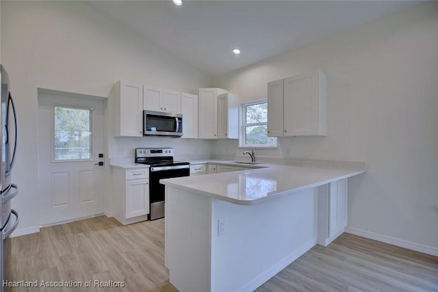 kitchen featuring a peninsula, a sink, light countertops, white cabinets, and appliances with stainless steel finishes