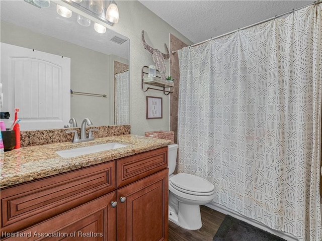 1954 Heard Rd, Wauchula, FL 33873 - full bath with vanity, toilet, visible vents, a textured ceiling, and wood finished floors
