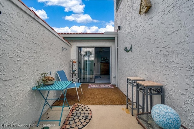 entrance to property featuring a patio, a tiled roof, and stucco siding