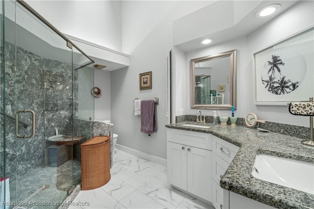 full bathroom featuring a sink, baseboards, marble finish floor, double vanity, and a stall shower