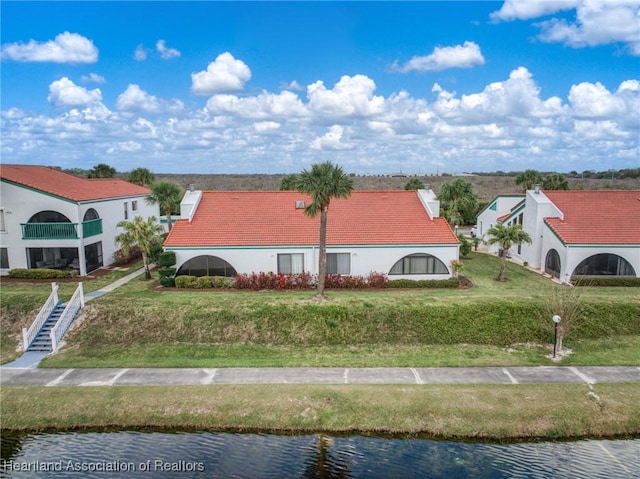 view of front of house featuring a water view, a tile roof, and a front yard