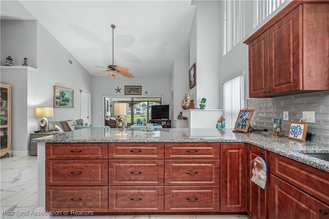 kitchen with plenty of natural light, marble finish floor, light stone counters, and a peninsula