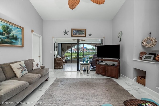 living area featuring a ceiling fan, marble finish floor, and baseboards