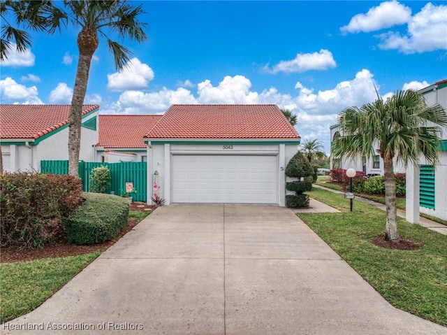 mediterranean / spanish-style home featuring a tiled roof, fence, concrete driveway, and stucco siding