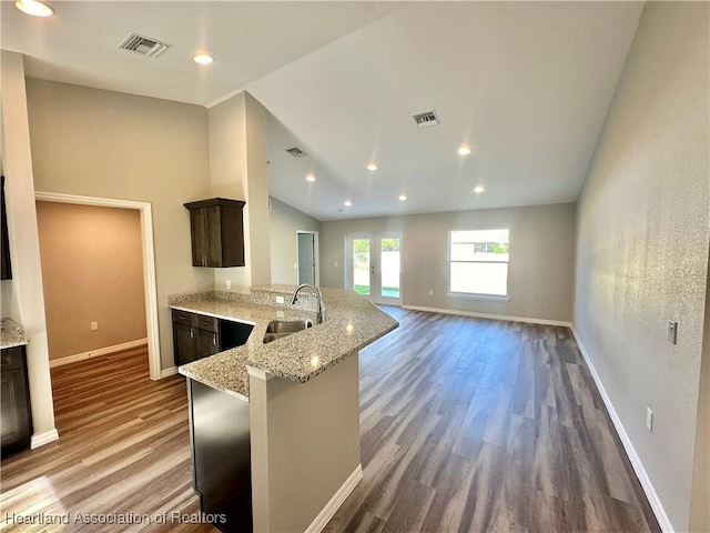 kitchen featuring light stone countertops, french doors, dark brown cabinets, dark wood-type flooring, and sink