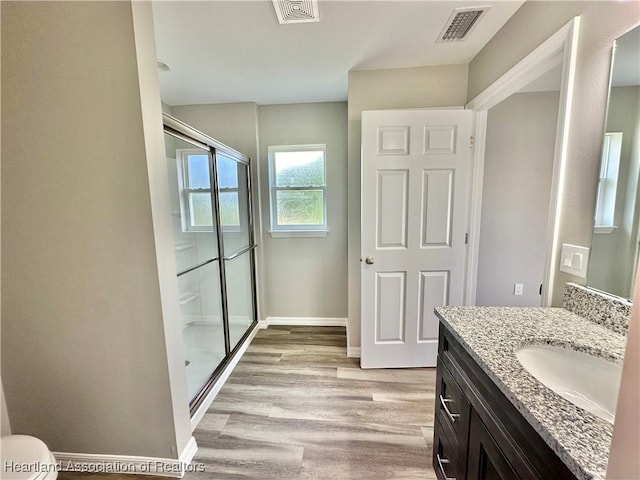 bathroom with hardwood / wood-style flooring, vanity, and a shower with door