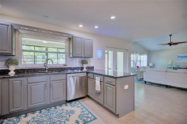 kitchen with a peninsula, plenty of natural light, a sink, gray cabinets, and stainless steel dishwasher