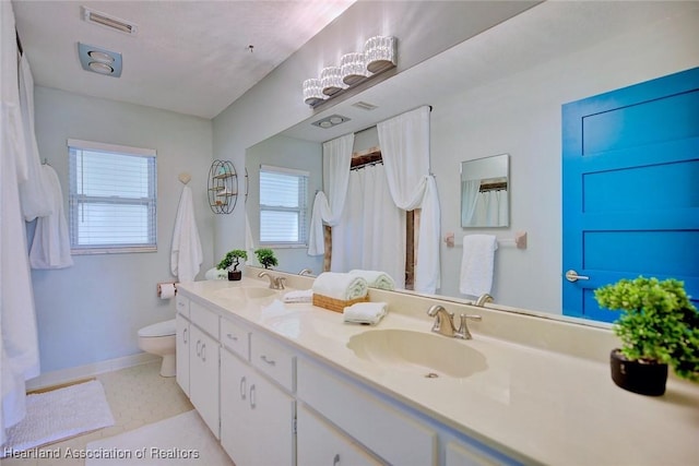 bathroom with toilet, a sink, double vanity, and visible vents