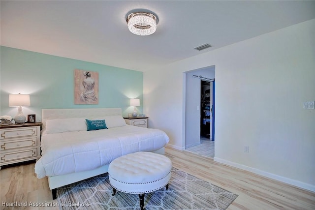 bedroom featuring baseboards, visible vents, and wood finished floors