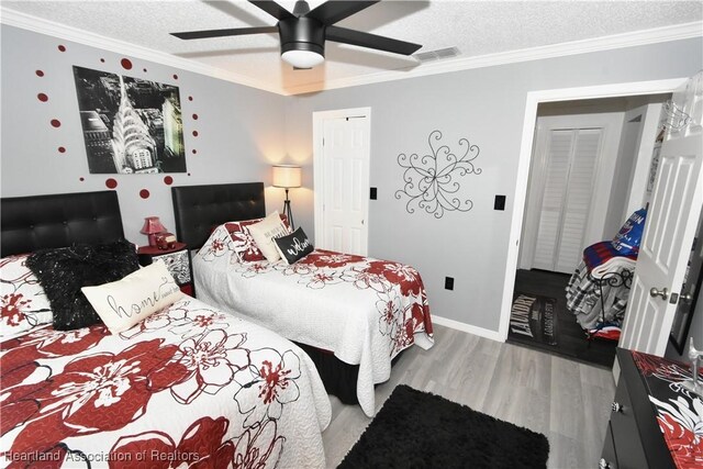 bedroom with visible vents, wood finished floors, a textured ceiling, and ornamental molding