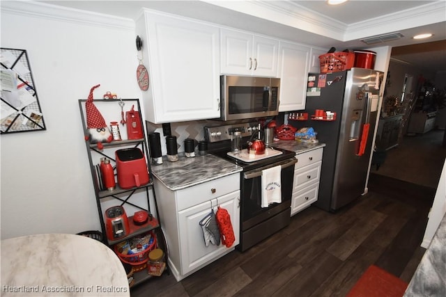 kitchen with white cabinets, dark countertops, dark wood-style floors, ornamental molding, and stainless steel appliances