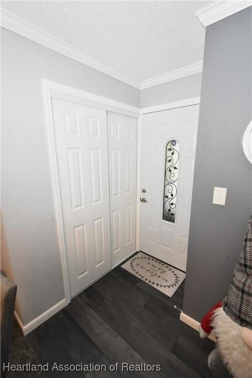 foyer entrance with baseboards, a textured ceiling, ornamental molding, and dark wood-style flooring