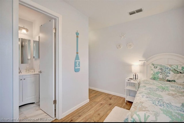 bedroom with ensuite bathroom and light hardwood / wood-style flooring