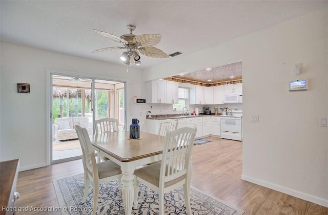 dining area featuring ceiling fan, sink, and light hardwood / wood-style flooring