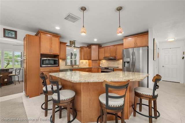 1904 Mulligan Rd, Sebring, FL 33872 - kitchen featuring stainless steel appliances, under cabinet range hood, light stone countertops, hanging light fixtures, and backsplash