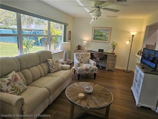 living area featuring dark wood finished floors, visible vents, a textured ceiling, and baseboards