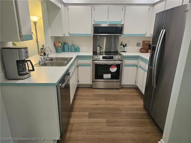 kitchen featuring a sink, tasteful backsplash, wood finished floors, stainless steel appliances, and light countertops