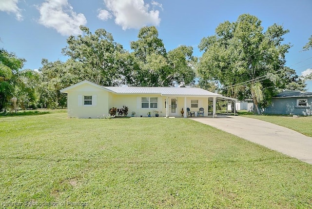 ranch-style home featuring an attached carport, driveway, metal roof, and a front yard