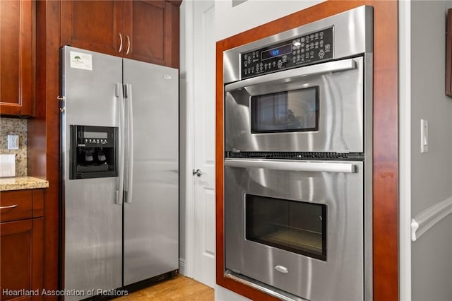 kitchen featuring appliances with stainless steel finishes, backsplash, and light stone counters