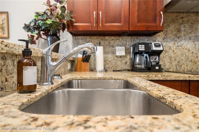 details with light stone countertops, sink, range hood, and tasteful backsplash