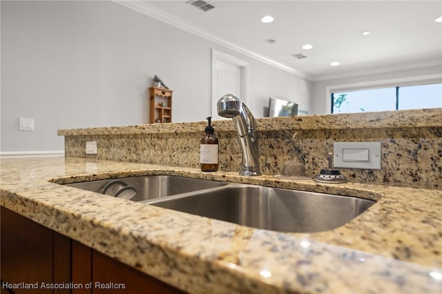 kitchen featuring sink, light stone counters, and ornamental molding