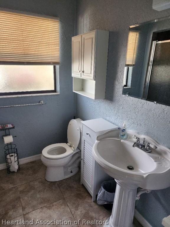 bathroom with toilet, tile patterned floors, and walk in shower