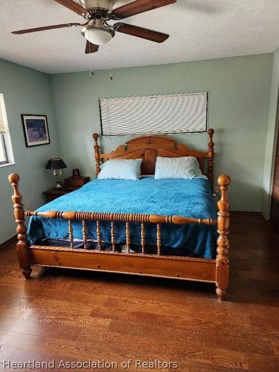 bedroom with ceiling fan, hardwood / wood-style floors, and a textured ceiling