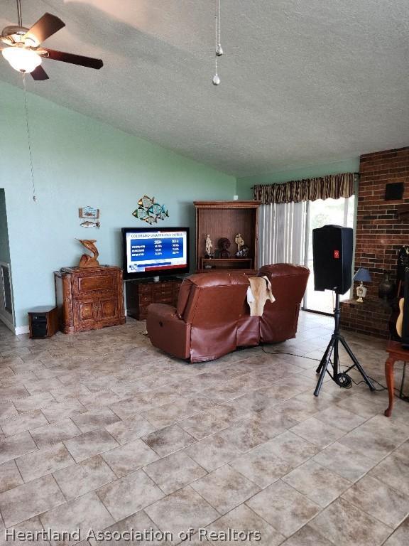 living room with vaulted ceiling, ceiling fan, and a textured ceiling