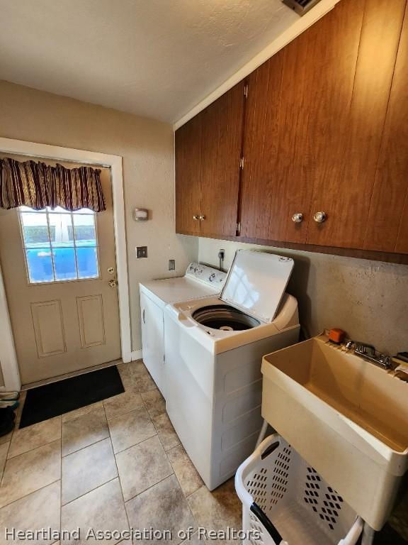 laundry room with cabinets, light tile patterned flooring, washer and clothes dryer, and sink