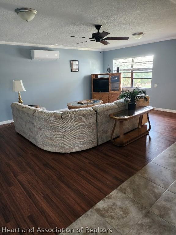 living room featuring a textured ceiling, ceiling fan, dark hardwood / wood-style flooring, and a wall mounted air conditioner