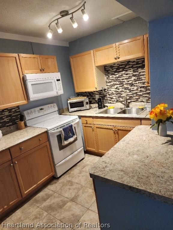 kitchen with decorative backsplash, white appliances, sink, and light tile patterned floors