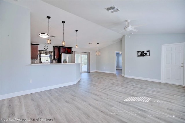 unfurnished living room with vaulted ceiling, ceiling fan with notable chandelier, and light hardwood / wood-style flooring